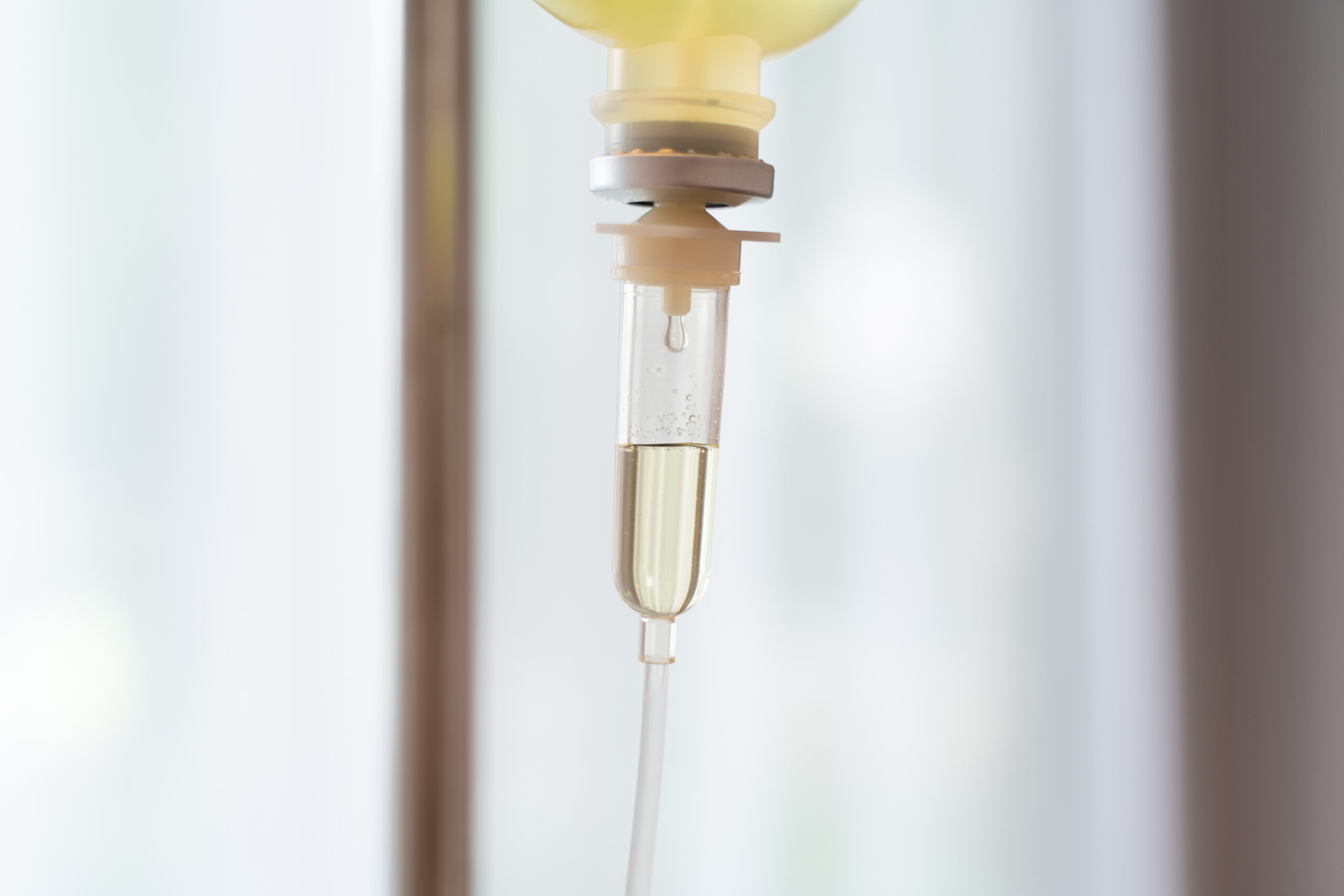 Close-up of an IV drip chamber delivering an amber vitamin solution