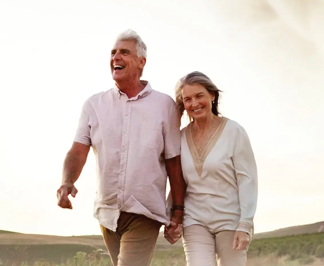 Smiling older couple walking outdoors at sunset
