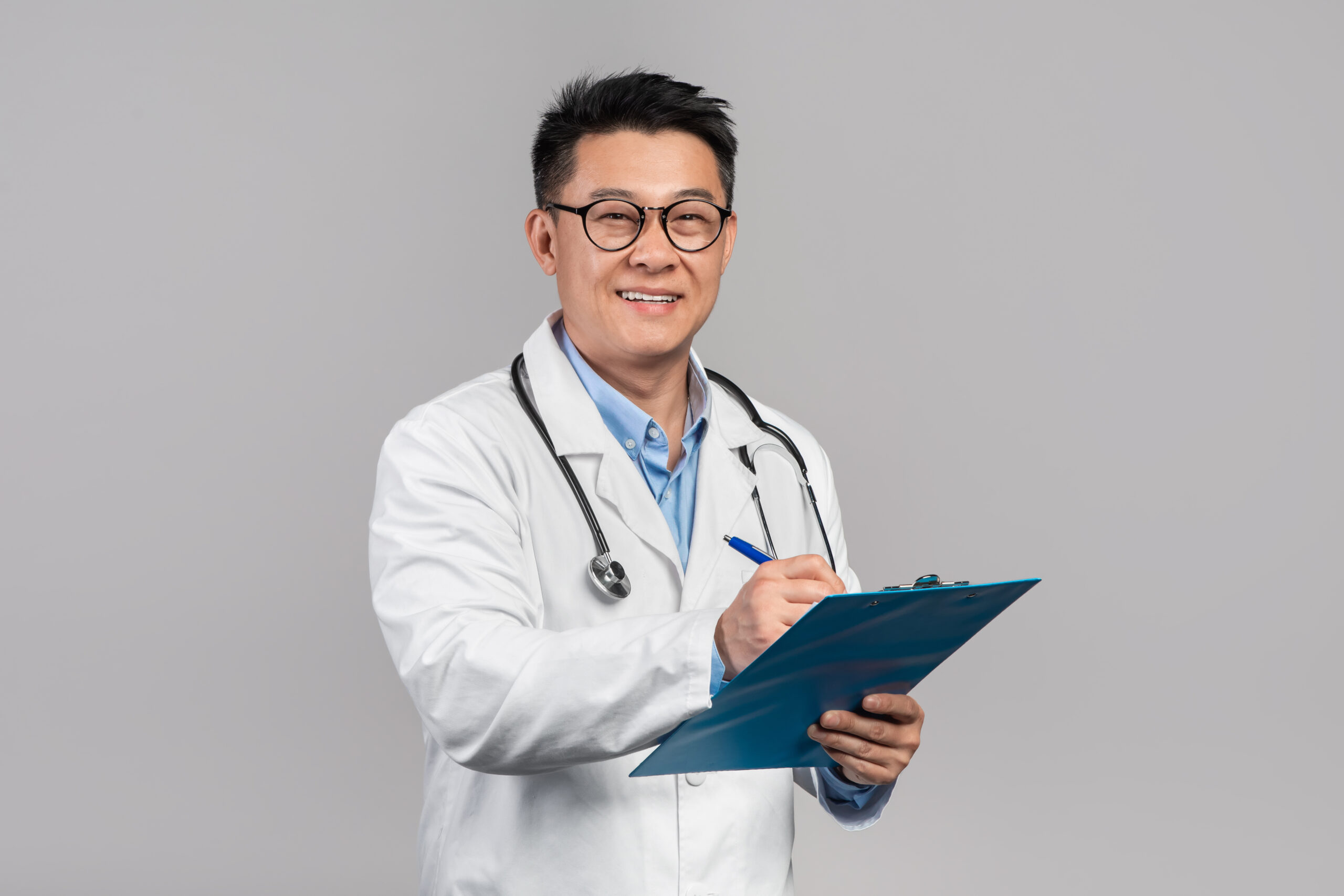 Doctor in a white coat and stethoscope writing on a clipboard